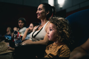 profile photo of an expectant little boy watching a movie in the cinema with his mother