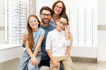 Portrait of young happy family wearing stylish eyeglasses sitting in  optical store. Vision concept  - obrazy, fototapety, plakaty