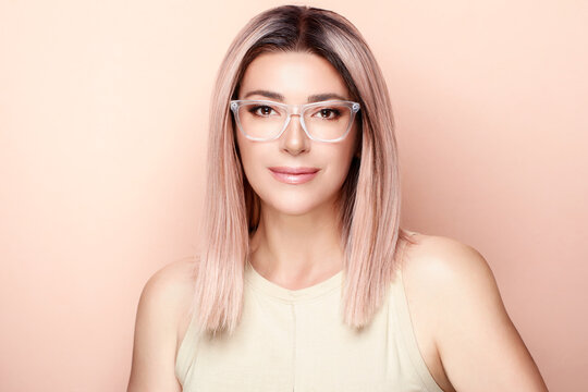 Smiling woman with long hair and glasses poses for studio portrait. With copyspace.