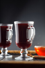 Close-up of glass with hot mulled wine and ingredients on dark background. Christmas drink concept