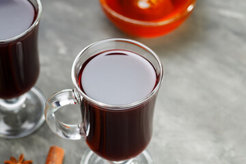 Two glasses of mulled wine with honey and spices on concrete background. Copy space
