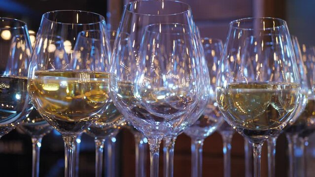 Glasses of white wine on a buffet table at an event beautifully lined up in evening light with blurry lights close-up