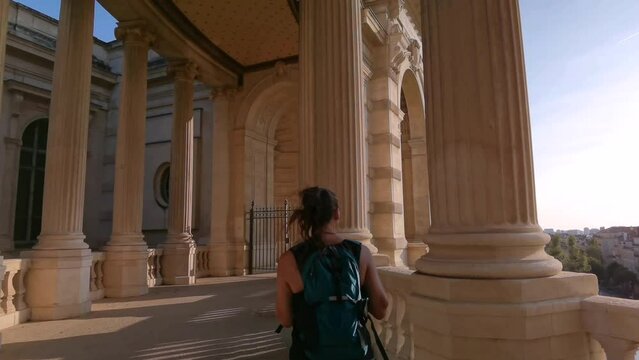 tourist girl walking between the columns of the Longchamp Palace