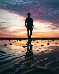 Silhouette of a man walking on a beach at dusk