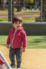 Fototapeta premium Little boy standing in the playground at the park.