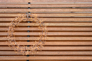 Wire and twinkle light wreath hanging on a modern wood wall
