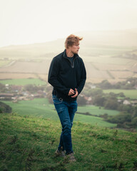 A man takes in the view as he walks on a windy hill