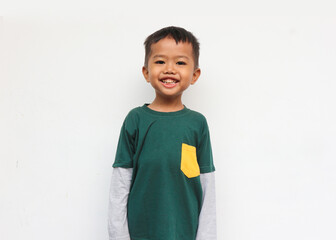 Happy smilling boy wearing layered long sleeve t-shirt standing and looking at camera. Isolated on...