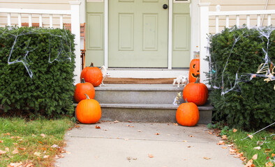 Halloween decorations adorn a haunted house front yard, featuring pumpkins, ghosts, and cobwebs,...