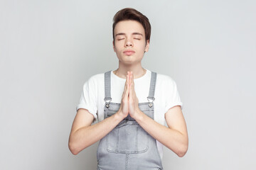 Man standing holding hands in namaste or prayer, keeping eyes closed while practicing yoga and...