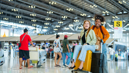 Happy woman friends holding passport and luggage walking together to airline check in counter in airport terminal. Attractive girl enjoy and fun travel on holiday vacation with airplane transportation - obrazy, fototapety, plakaty