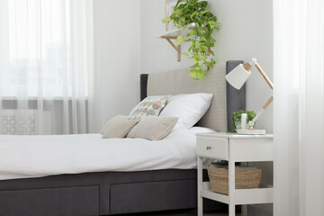 Stylish bedroom interior with large comfortable bed and bedside table