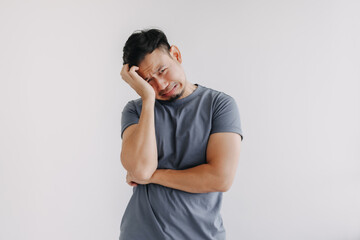 Sad funny face asian man in blue t-shirt crying stand isolated on white.