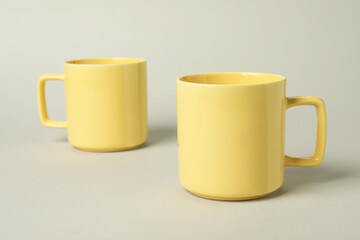 Two yellow ceramic mugs on light grey background