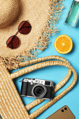 Flat lay composition with wicker bag and other beach accessories on light blue background