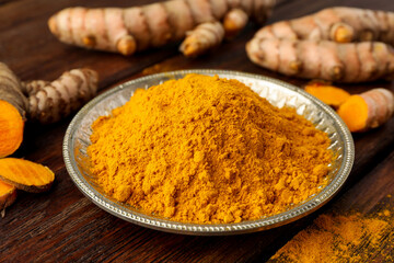 Plate with aromatic turmeric powder on wooden table, closeup