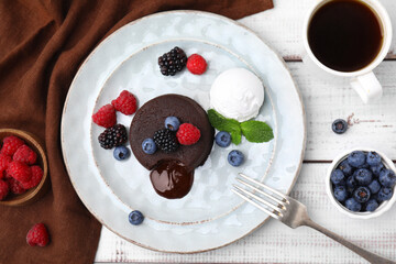 Delicious chocolate fondant served with fresh berries and ice cream on white wooden table, flat lay
