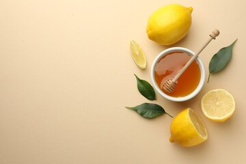 Ripe lemons, leaves, bowl of honey and dipper on beige background, flat lay. Space for text
