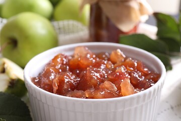 Bowl of delicious apple jam and fresh fruits on white tablecloth, closeup