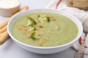 Delicious broccoli cream soup served on light table, closeup
