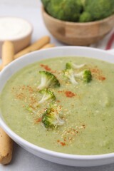 Delicious broccoli cream soup served on light table, closeup