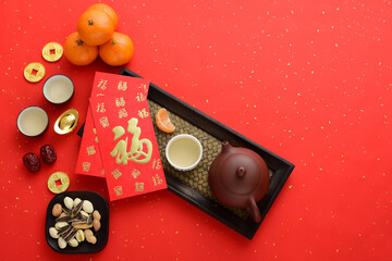 Kung Fu tea, snacks, fruits, ingots, and red envelopes on a red background. The Chinese meaning in the picture is: Blessing