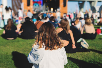 Crowded open air festival concert with scene lights with musicians band on stage at the venue, rock show performance, with concert-goers attendees, audience on dance floor during summer festival