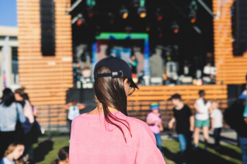 Crowded open air festival concert with scene lights with musicians band on stage at the venue, rock show performance, with concert-goers attendees, audience on dance floor during summer festival