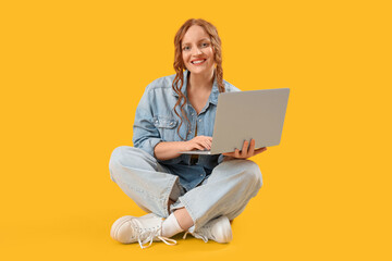 Beautiful redhead woman using laptop on yellow background