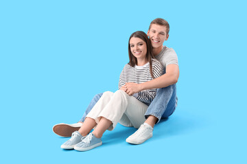 Happy young couple hugging on blue background