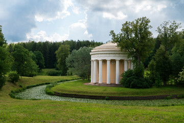 Fototapeta na wymiar View of the Temple of Friendship on the bank of the Slavyanka River in the Pavlovsky Park on a sunny summer day, Pavlovsk, Saint Petersburg, Russia