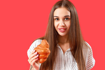 Beautiful happy young woman with tasty croissant on red background