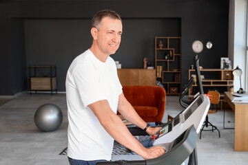 Sporty mature man training on treadmill at home