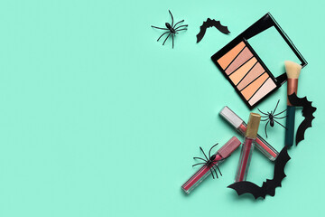 Lipsticks and different decorative cosmetics with Halloween decor on green background
