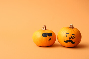 Funny Halloween pumpkins with drawn faces on orange background