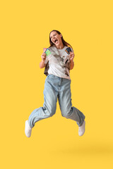 Fototapeta na wymiar Young woman with credit cards jumping on yellow background