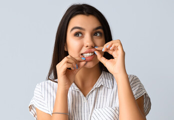 Young woman with healthy teeth on light background, closeup