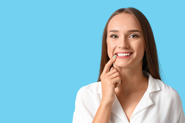 Smiling young woman with healthy teeth on blue background