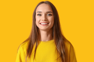 Smiling young woman with healthy teeth on yellow background, closeup