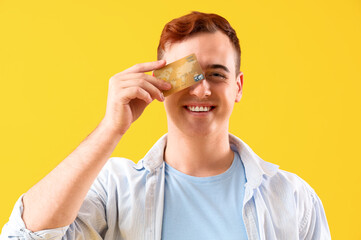 Young man with credit card on color background, closeup