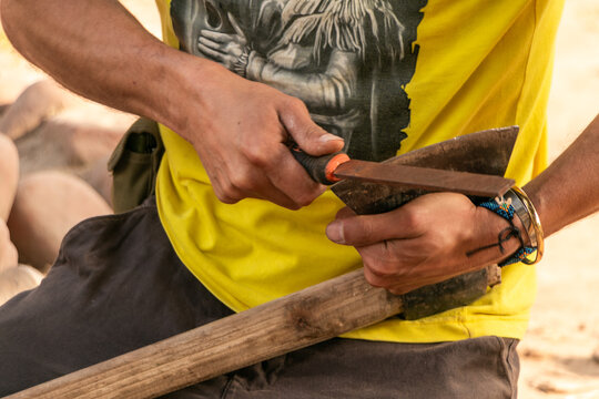 man working sharpening an ax with a file