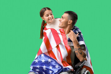 Soldier in wheelchair with USA flag and his little daughter on green background. Veterans Day celebration