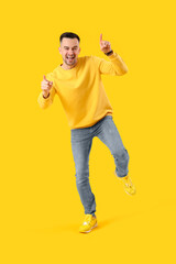 Fototapeta na wymiar Happy young man pointing at something on yellow background