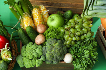 Boxes with fresh vegetables on green background, closeup