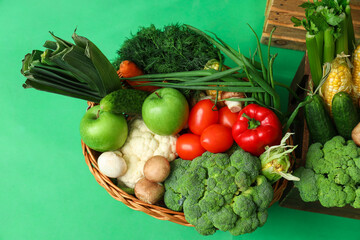 Basket with fresh vegetables on green background