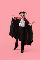 Little boy dressed for Halloween as vampire on pink background