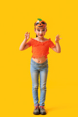 Little girl dressed for Halloween on yellow background