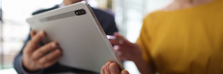 Man shows woman accounting information on website via tablet