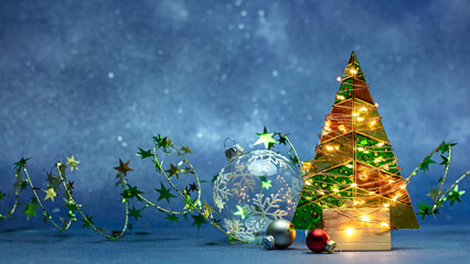 christmas tree decorated by glowing holiday lights with new year balls on blue background.