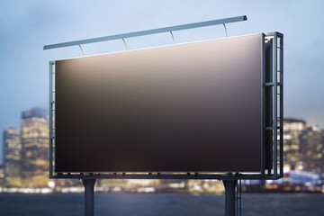 Fototapeta premium Blank black billboard on cityscape background at evening, perspective view. Mock up, advertising concept